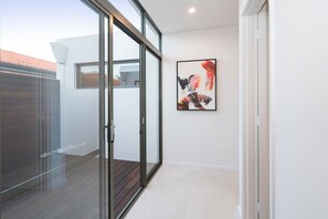 A modern interior with a glass door leading to an outdoor area, a framed abstract painting on the wall, and a clean, minimalist design.