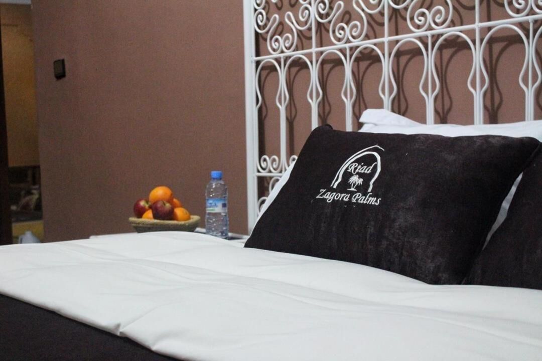 Una habitación de hotel con una cama bien hecha, un cabecero de metal decorativo y un frutero en la mesita de noche.