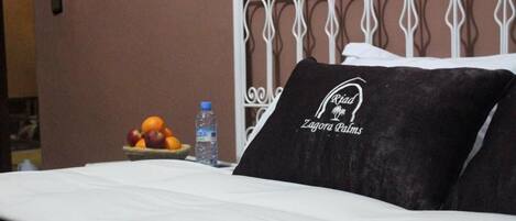 Una habitación de hotel con una cama bien hecha, un cabecero de metal decorativo y un frutero en la mesita de noche.