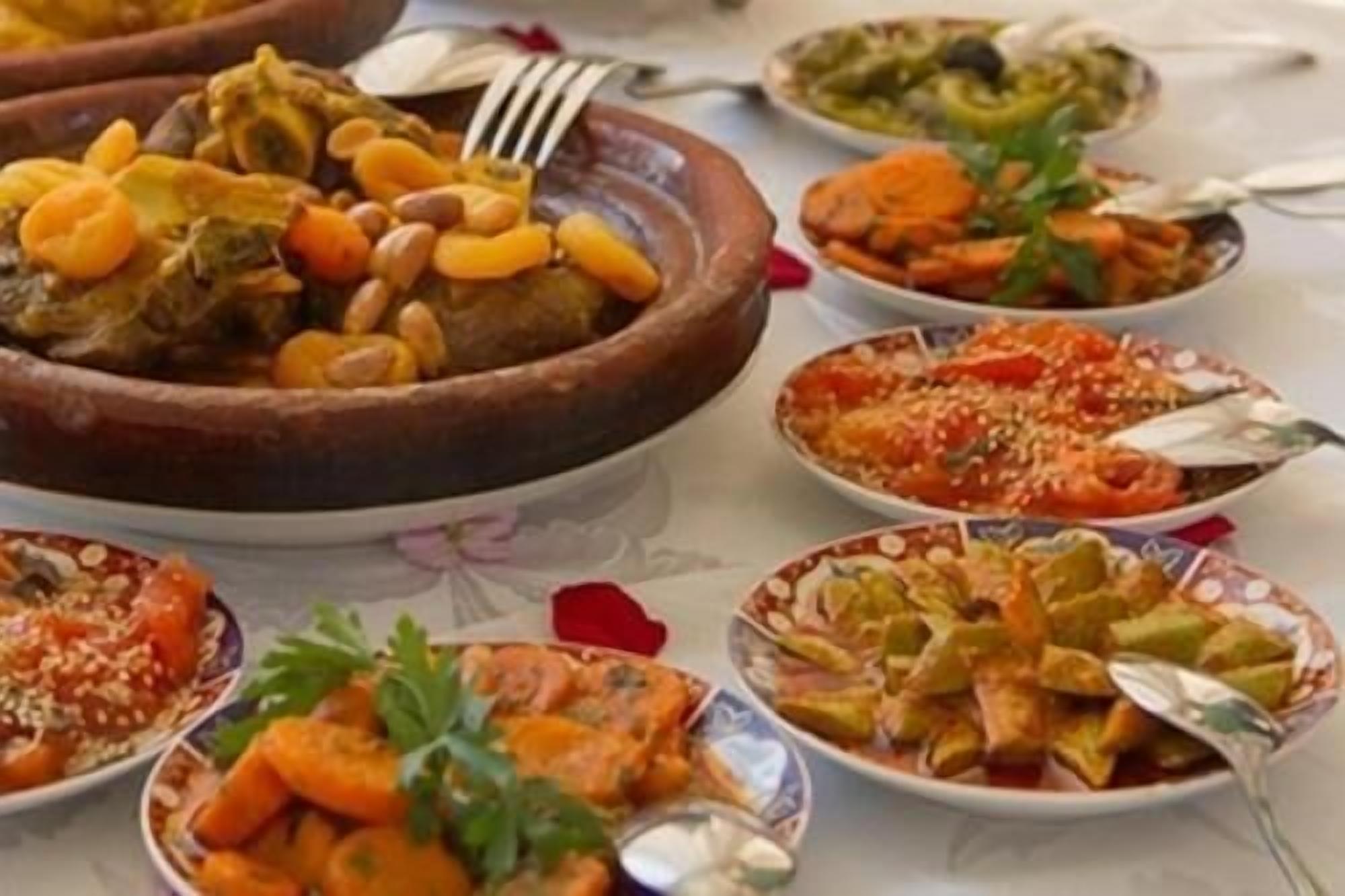 Verschillende gerechten op een tafel, waaronder een grote kom stoofpot en meerdere borden met diverse soorten eten.
