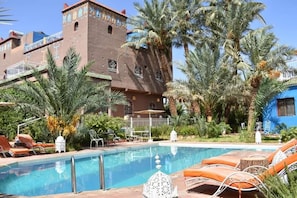 Un área de piscina con sillas de descanso y un edificio de arquitectura tradicional.
