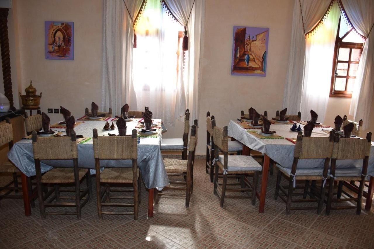 A dining area with multiple tables and chairs, decorated with various items and paintings on the walls.