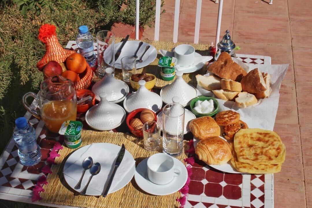 A breakfast setup with various food items and utensils on a table outdoors.