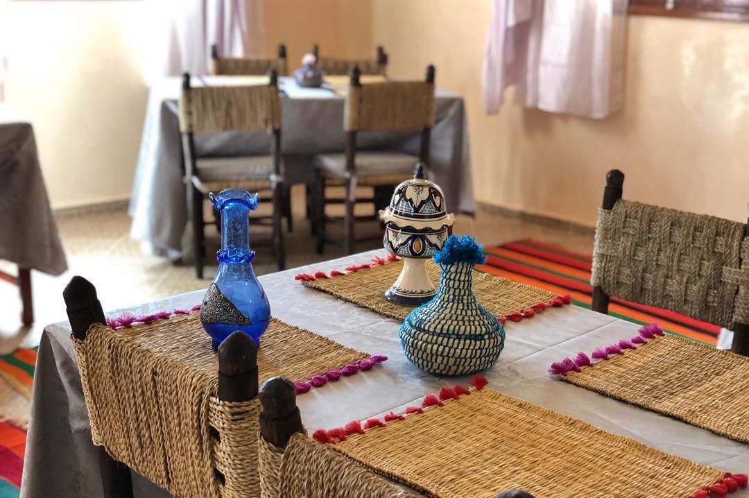 A dining table with woven placemats and decorative vases.