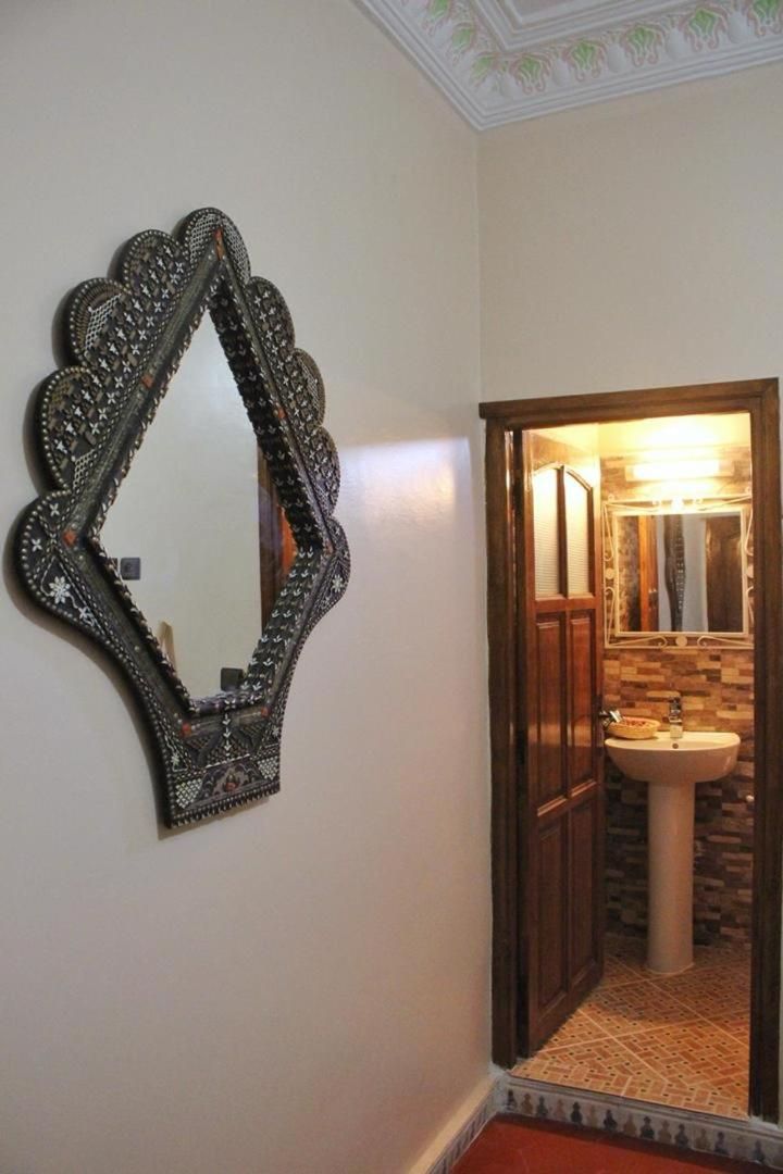 A bathroom with a decorative mirror, a sink, and a tiled floor.