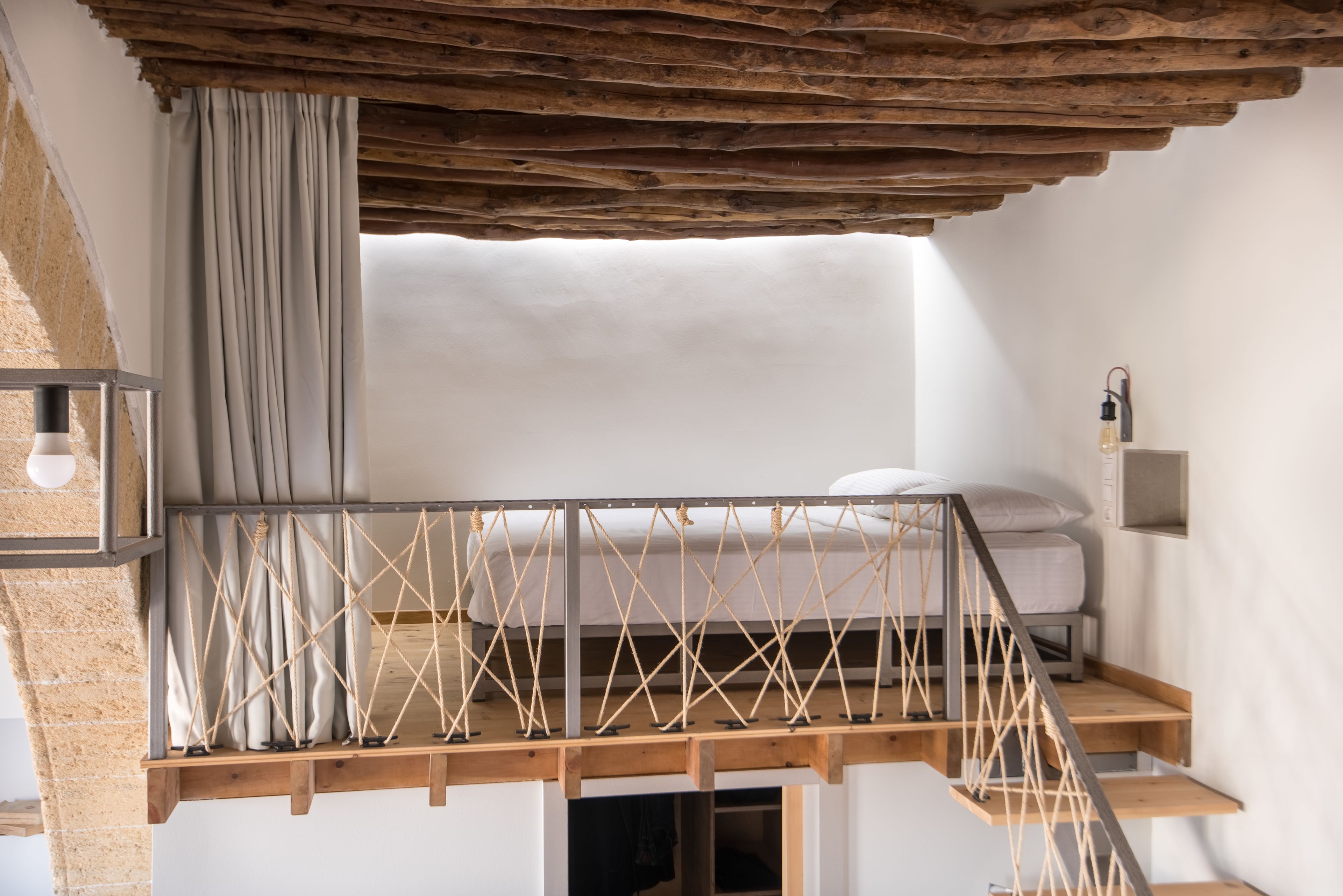 Ein Schlafzimmer im Loft-Stil mit einer Holztreppe, einem Bett und einem kleinen Tisch.