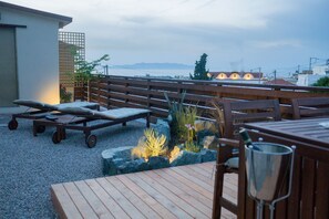 A rooftop terrace with wooden furniture, a small garden, and a view of the cityscape and mountains in the distance. - Villa Acacia (Rhodes)