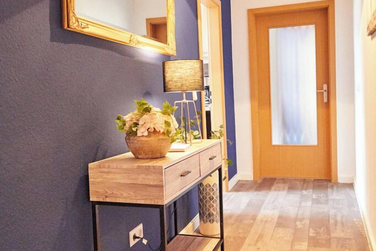 A hallway with a wooden console table, a mirror, and a pendant light.