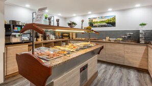 A buffet setup with various food items and a coffee machine. - Cityhotel Bernburg (Bernburg)