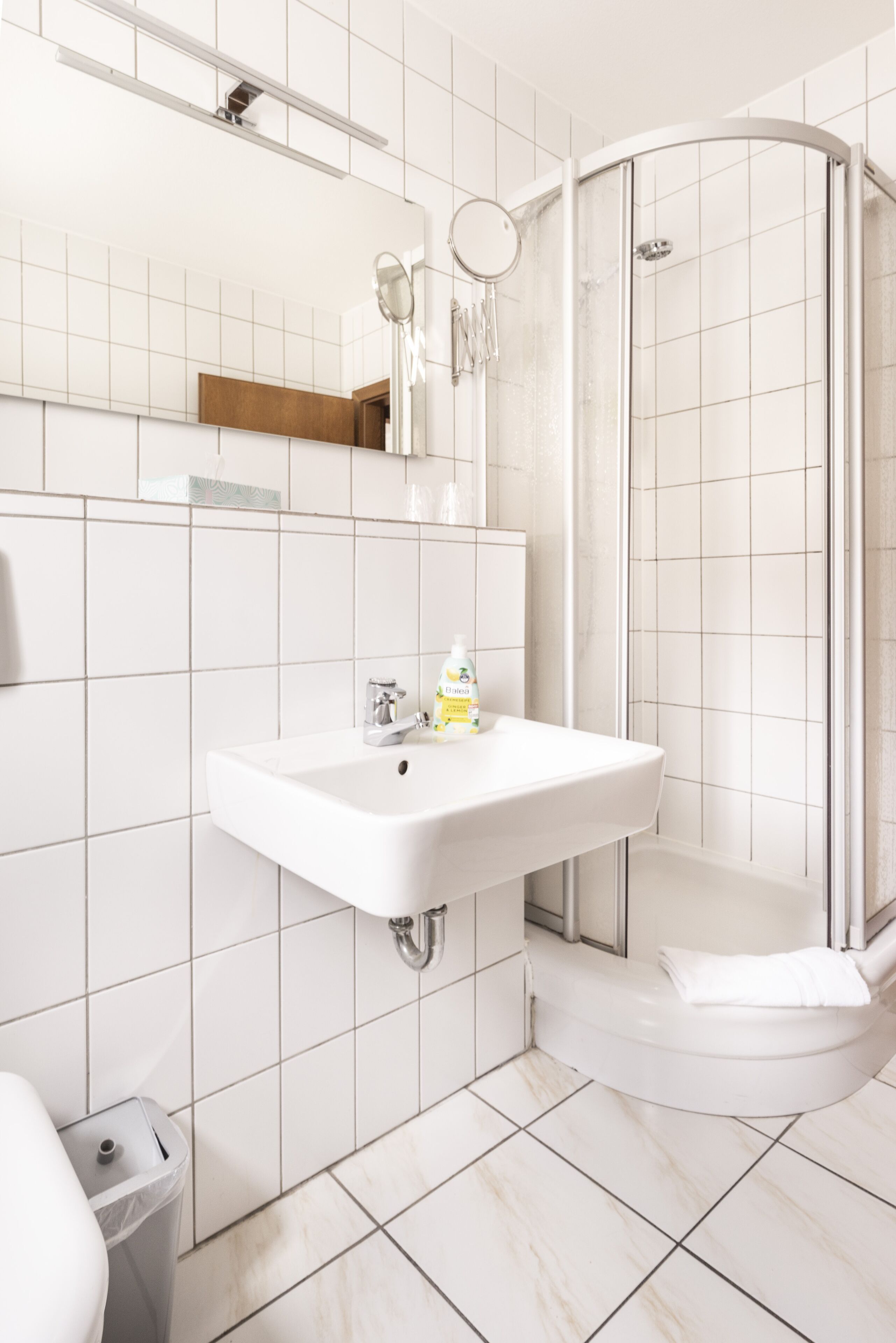 A bathroom with a white sink, a mirror, and a shower enclosure.