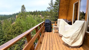 Um deck de madeira com guarda-corpo, com vista para uma área arborizada.