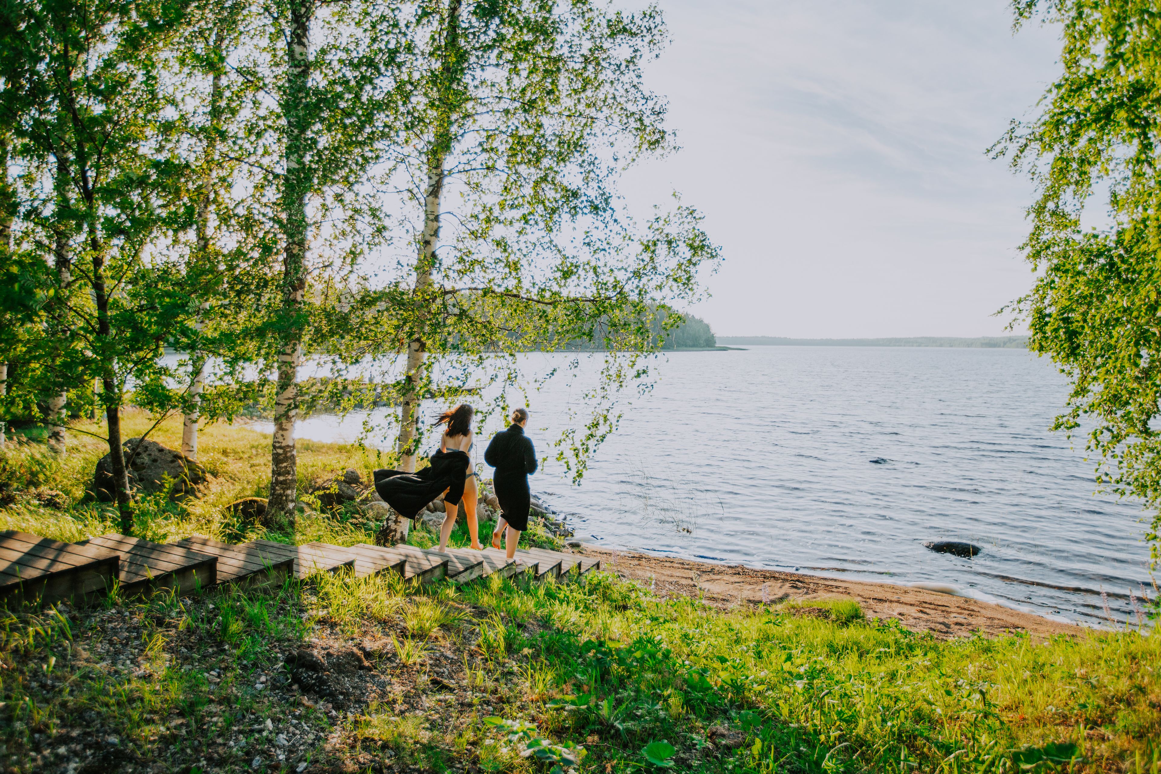 A lakeside scene with a wooden deck and a grassy area.