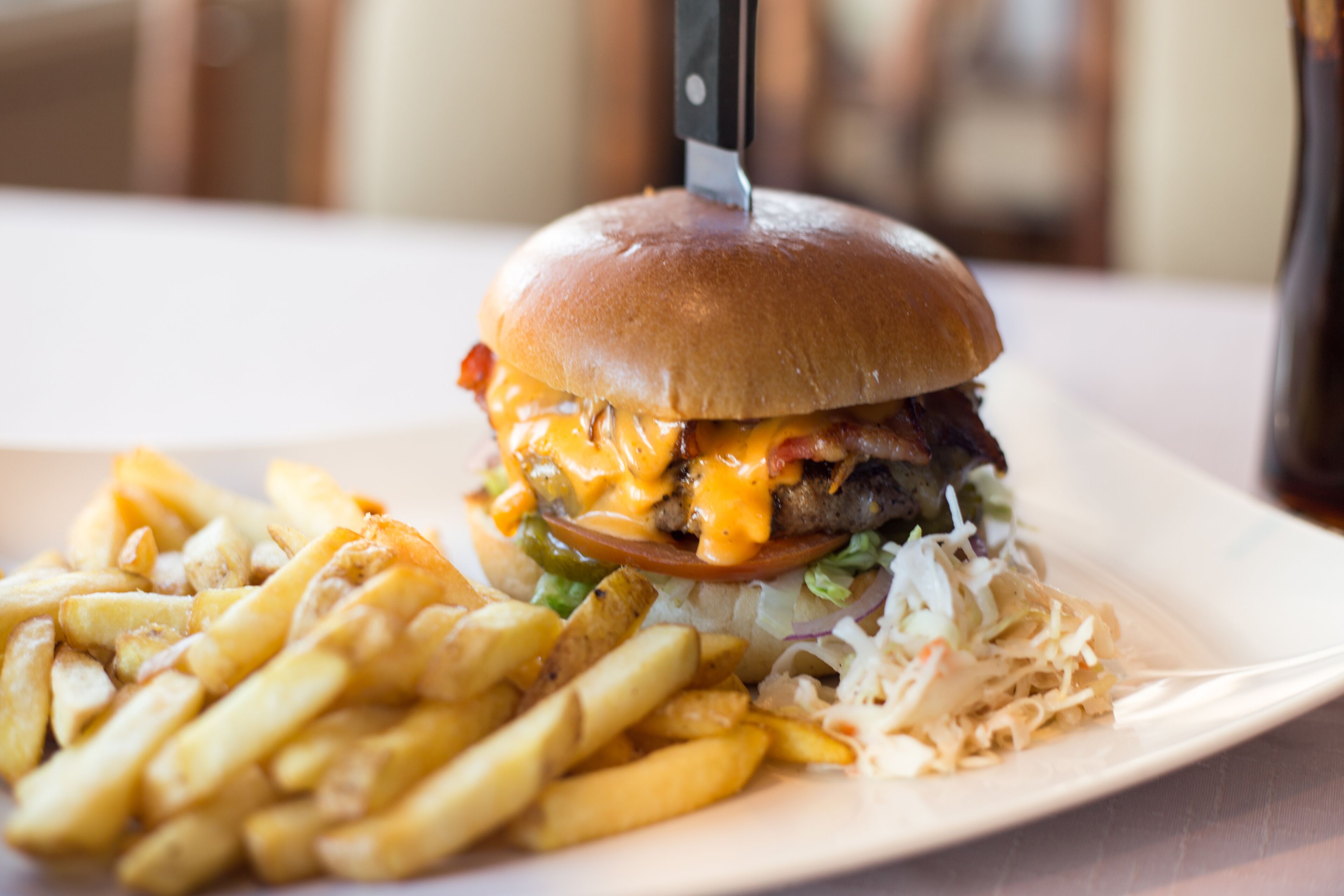 Hamburguesa con papas fritas y ensalada de col en un plato.