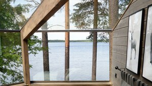 A bedroom with a large bed, a view of a lake, and wooden walls. - Revontuli Resort Glass Igloos (Hankasalmi)