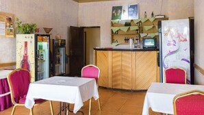 Un restaurante con mesas y sillas, una zona de bar y un refrigerador con un diseño colorido.