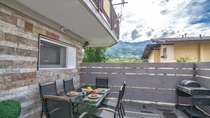 An outdoor patio with a glass table, chairs, and a grill. - Da Chris e Lisa 022205-AT-296296 (Trento)