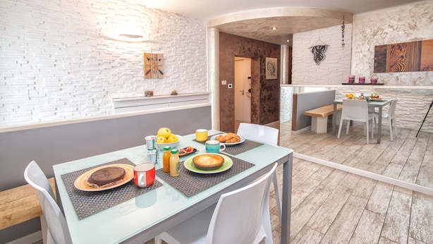 A modern kitchen with white brick walls, a dining table with chairs, and a breakfast setting. - Da Chris e Lisa 022205-AT-296296 (Trento)