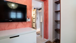 A room with a TV mounted on a white cabinet, a red wall, and a wooden floor. - Da Chris e Lisa 022205-AT-296296 (Trento)