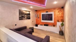 A modern living room with a flat-screen TV mounted on the wall, a sofa, a coffee table, and a decorative plant. - Da Chris e Lisa 022205-AT-296296 (Trento)