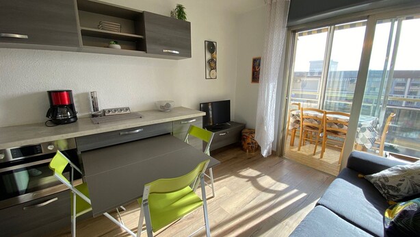 Une cuisine moderne avec un coin repas, un canapé et un balcon offrant une vue sur la ville.