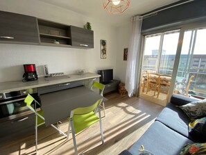 Una cocina moderna con comedor, sofá y balcón con vista a la ciudad.