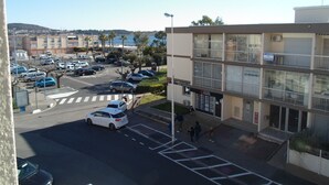 Un parking avec plusieurs voitures, un passage piéton et un bâtiment sur lequel on peut lire une pancarte indiquant « À LOUER ».