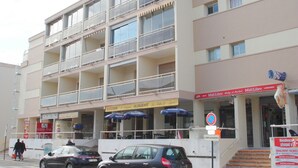 Un immeuble à plusieurs étages doté de balcons, d’un café et d’une devanture visible.