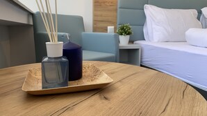 A modern hotel room with a wooden table, a blue sofa, a bed with white bedding, and a small potted plant. - besttime Hotel Monschau (Monschau)
