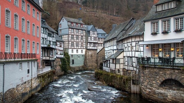 A narrow river running through a town with traditional half-timbered houses on both sides. - besttime Hotel Monschau (Monschau)