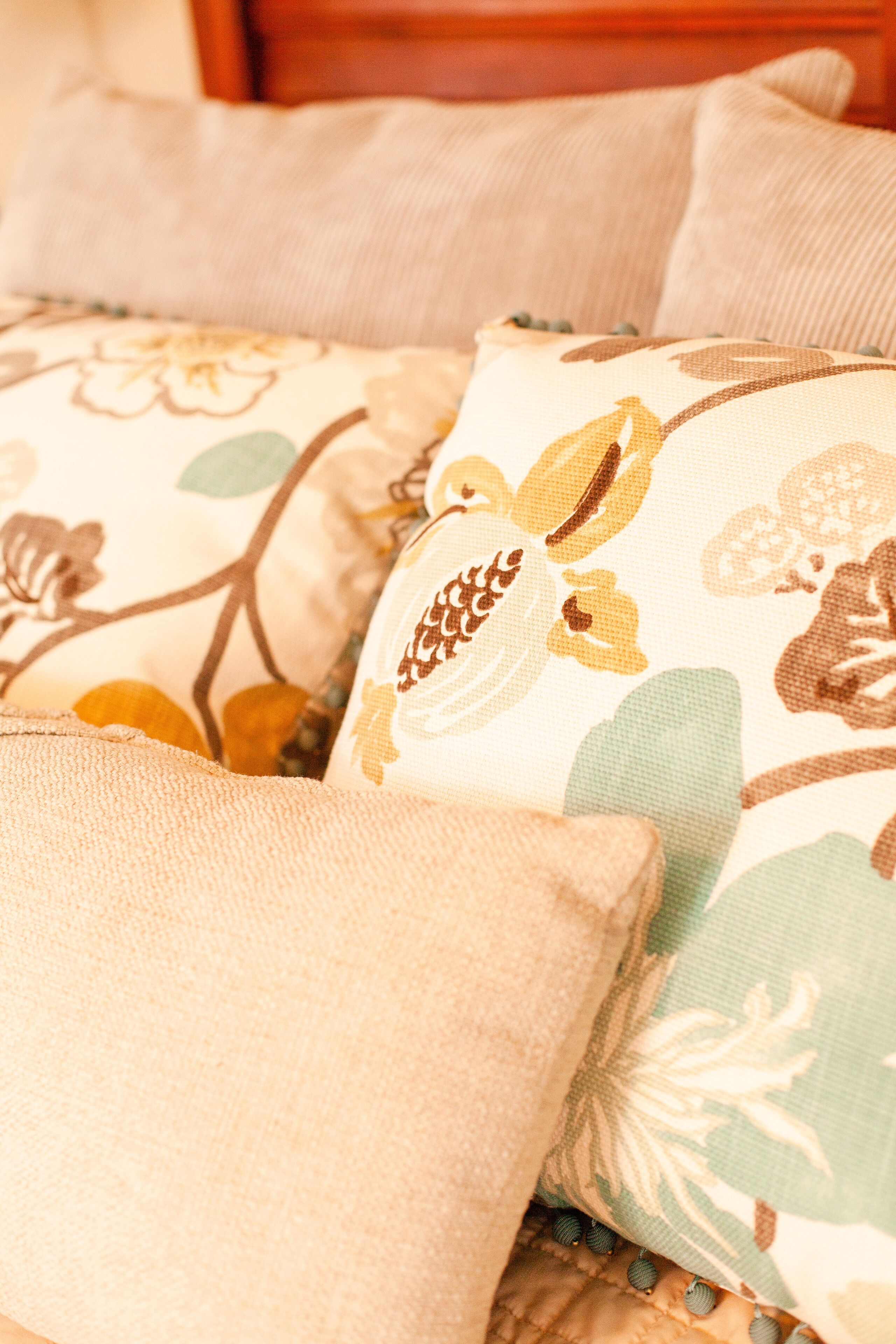 A close-up of a bed with floral-patterned pillows and a textured blanket.
