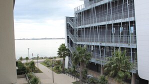 A modern building with a waterfront view, featuring a pedestrian walkway and palm trees. - Cozy apartment near thermal baths, pets allowed (Balaruc-les-Bains)