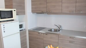 A compact kitchen with a microwave, sink, and wooden cabinets. - Cozy apartment near thermal baths, pets allowed (Balaruc-les-Bains)