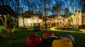 An outdoor area with seating, a covered structure, and string lights.