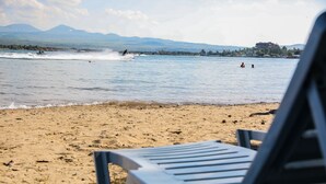A beach with a row of lounge chairs facing the water.