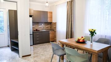 A modern kitchen with a wooden countertop and cabinets, a dining table with chairs, and a vase with flowers on the table.