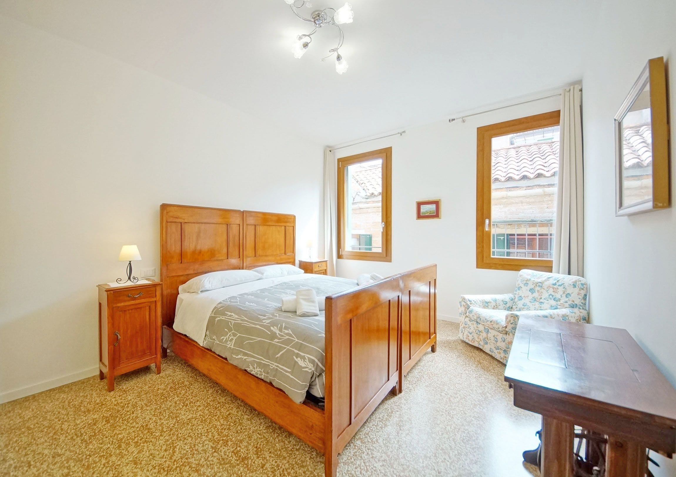 A bedroom with a wooden bed, a nightstand, a chair, and a desk.