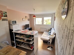 A compact living space with a kitchenette, a dining area, and a seating area with a view of the outdoors.
