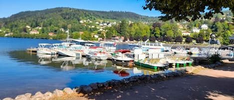 A marina with boats docked, a clear sky, and a hilly landscape in the background.