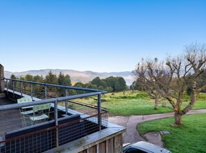 A balcony with a view of a green landscape and mountains.