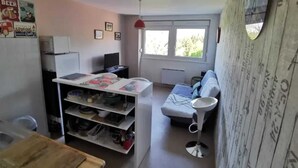 A compact living space with a kitchenette, a dining area, and a seating area with a sofa and a small table. - Homerez - Studio in Gérardmer (Gérardmer)