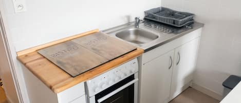 A compact kitchen with a built-in oven, a sink, and a wooden countertop.