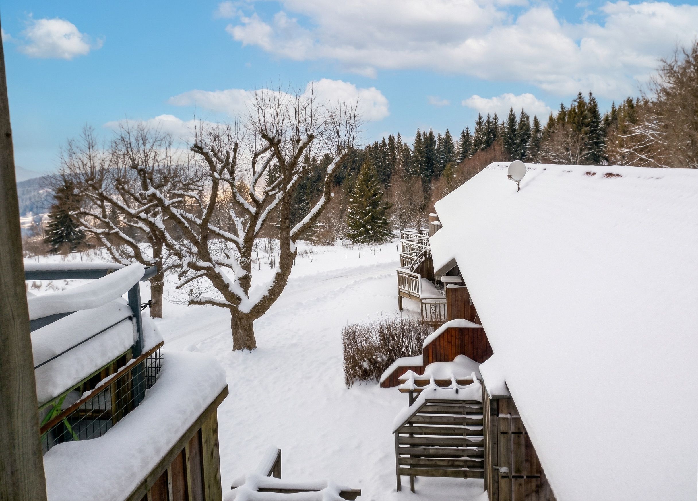 A snowy landscape with a wooden staircase leading up to a building with a snow-covered roof.