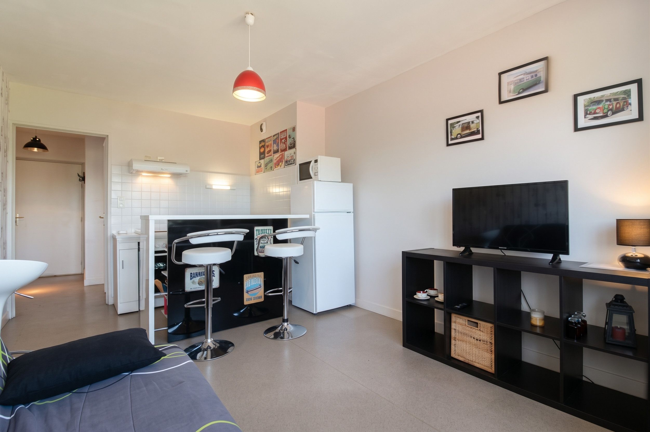 Un salon moderne avec un téléviseur à écran plat, un meuble de rangement noir et un canapé.