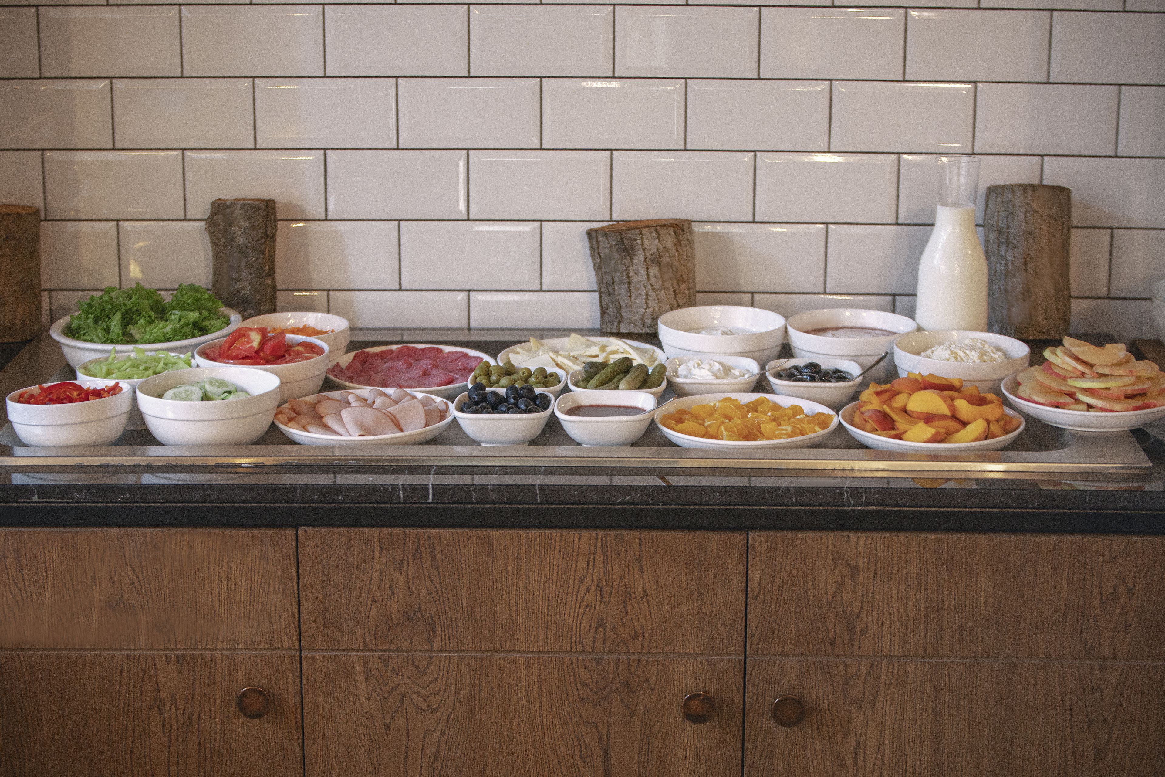 Una mesa de buffet con diversos alimentos y una jarrón de leche.