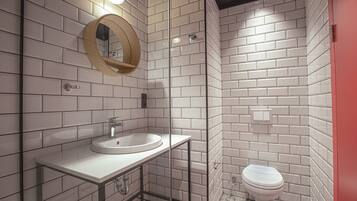 Une salle de bain moderne avec un lavabo blanc, un miroir rond et des toilettes.