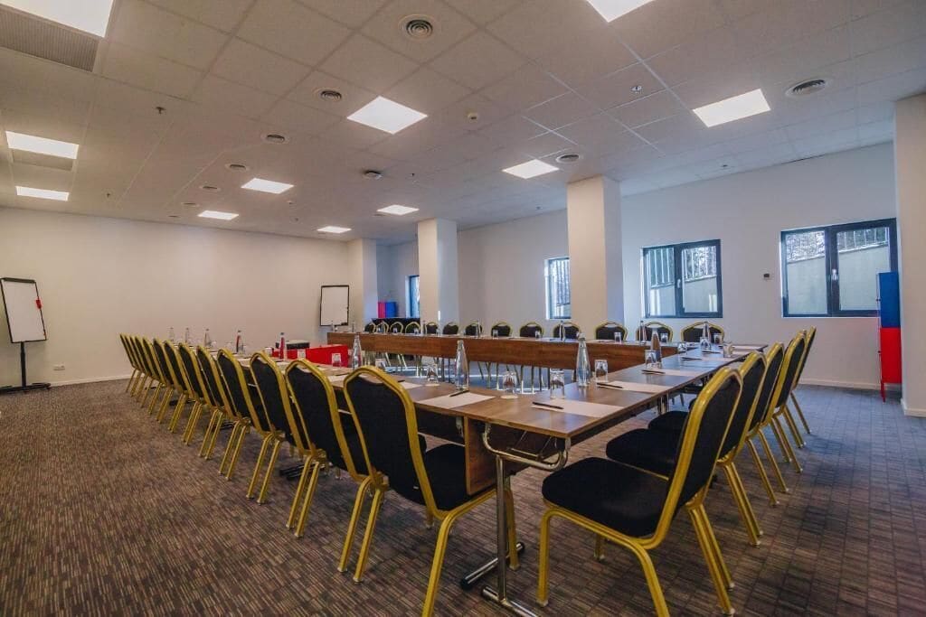 Un salón de conferencias con una larga mesa, sillas y una pizarra.