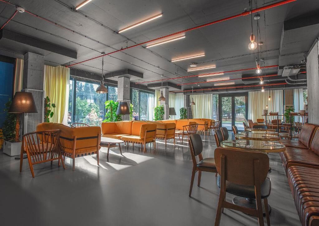 Amplia sala de estar con diversas opciones de asientos, incluyendo sofás y sillones, y ventanas grandes que aportan luz natural.