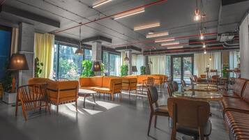 Amplia sala de estar con diversas opciones de asientos, incluyendo sofás y sillones, y ventanas grandes que aportan luz natural.