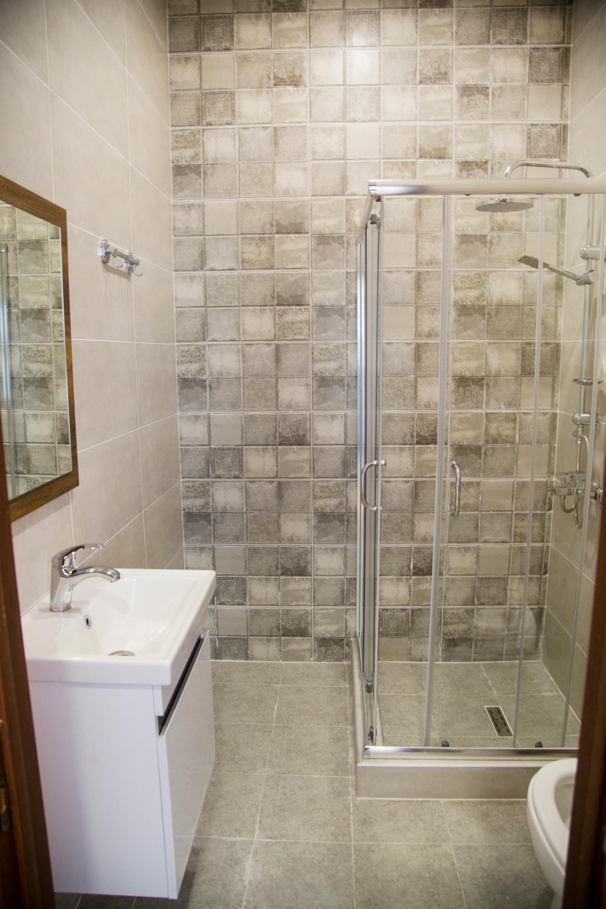 Un baño con ducha de cristal, lavamanos y espejo.