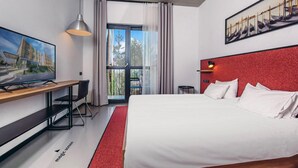 A modern hotel room with a large bed, a desk, a television, and a balcony with curtains. - Park Hotel Tsinandali Estate (Telavi)